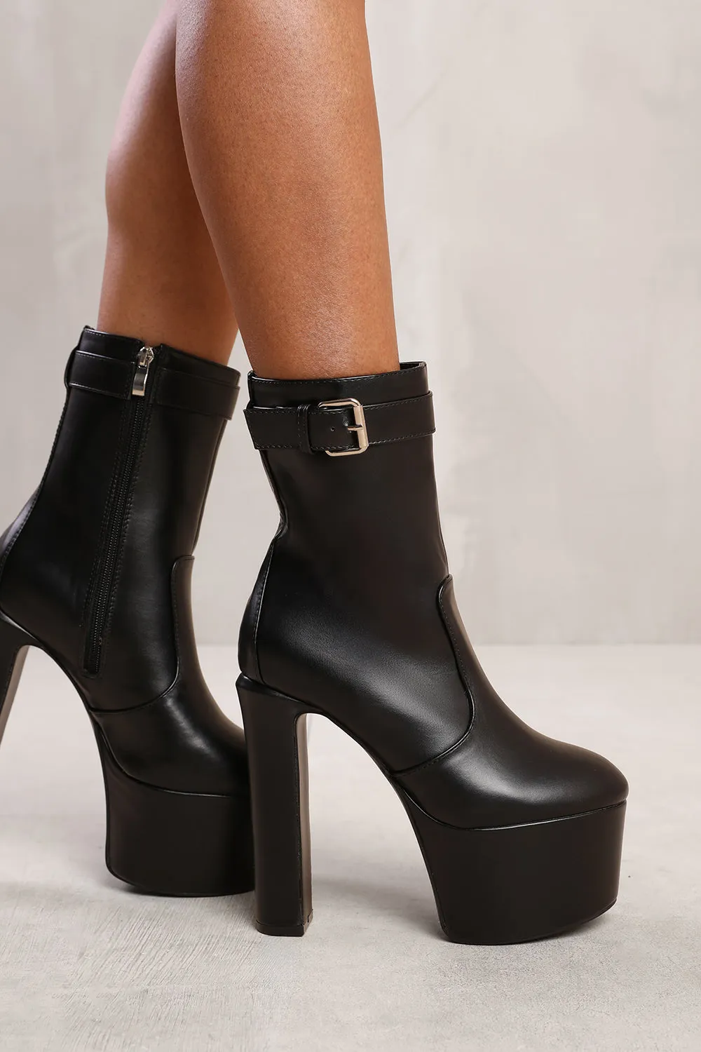 ADDISON PLATFORM HEELED ANKLE BOOT WITH BUCKLE DETAIL AND SIDE ZIP IN BLACK FAUX LEATHER